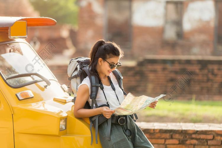 年轻的亚洲女性旅行者背包旅行站立在出租汽车或笃笃和看见地图旅行与